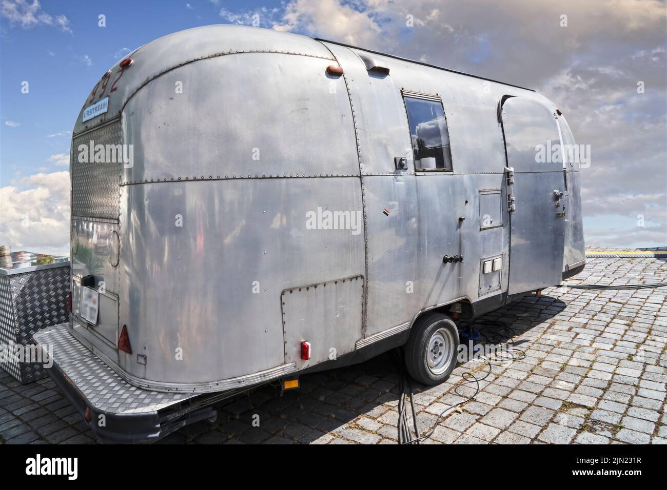 Airstream camper, vecchio esempio leggermente intemperiato del famoso veicolo americano fatto di piastre rivettate in alluminio ad Hannover, Germania, 23 luglio 2022 Foto Stock