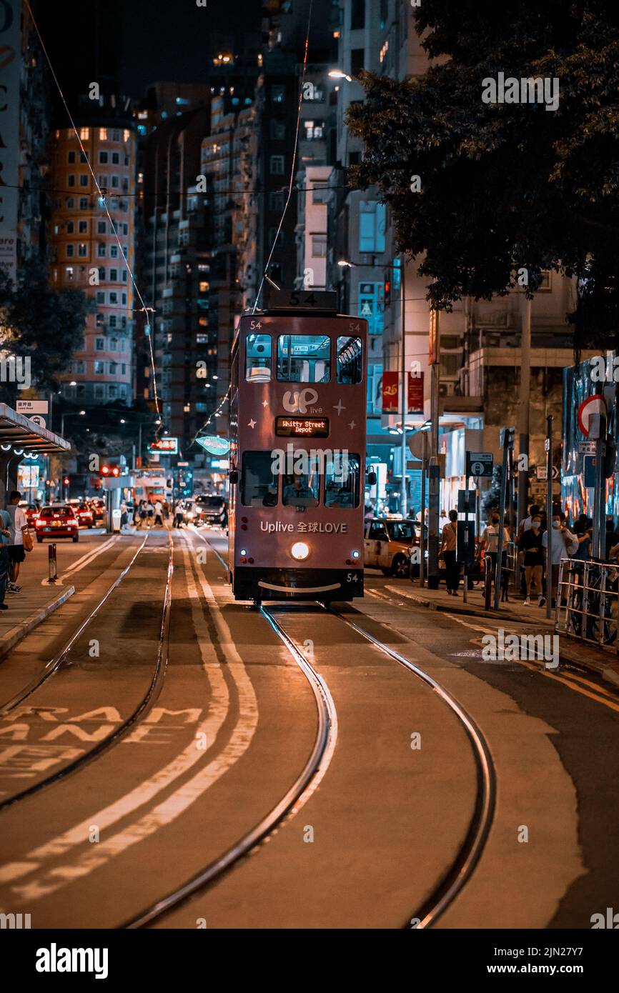 Uno scatto verticale di un tram ancora in esecuzione a tarda notte a Wanchai, Hong Kong Foto Stock