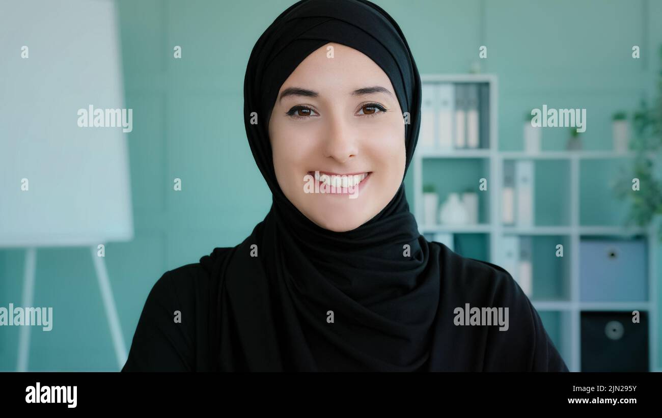 Ritratto femmina Happy Arabian 20s ragazza in nero hijab musulmana donna in posa in casa guardando la fotocamera guardando la fotocamera spensierata amichevole volto Foto Stock