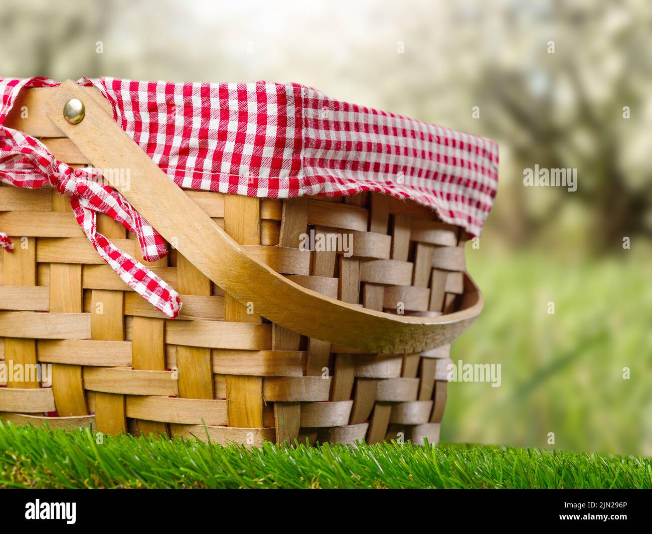 Primo piano. Cestino da picnic con paglia su un prato verde sullo sfondo della natura. Attività ricreative all'aperto, ecologia, romanticismo, tradizioni di famiglia, vacanza con f Foto Stock