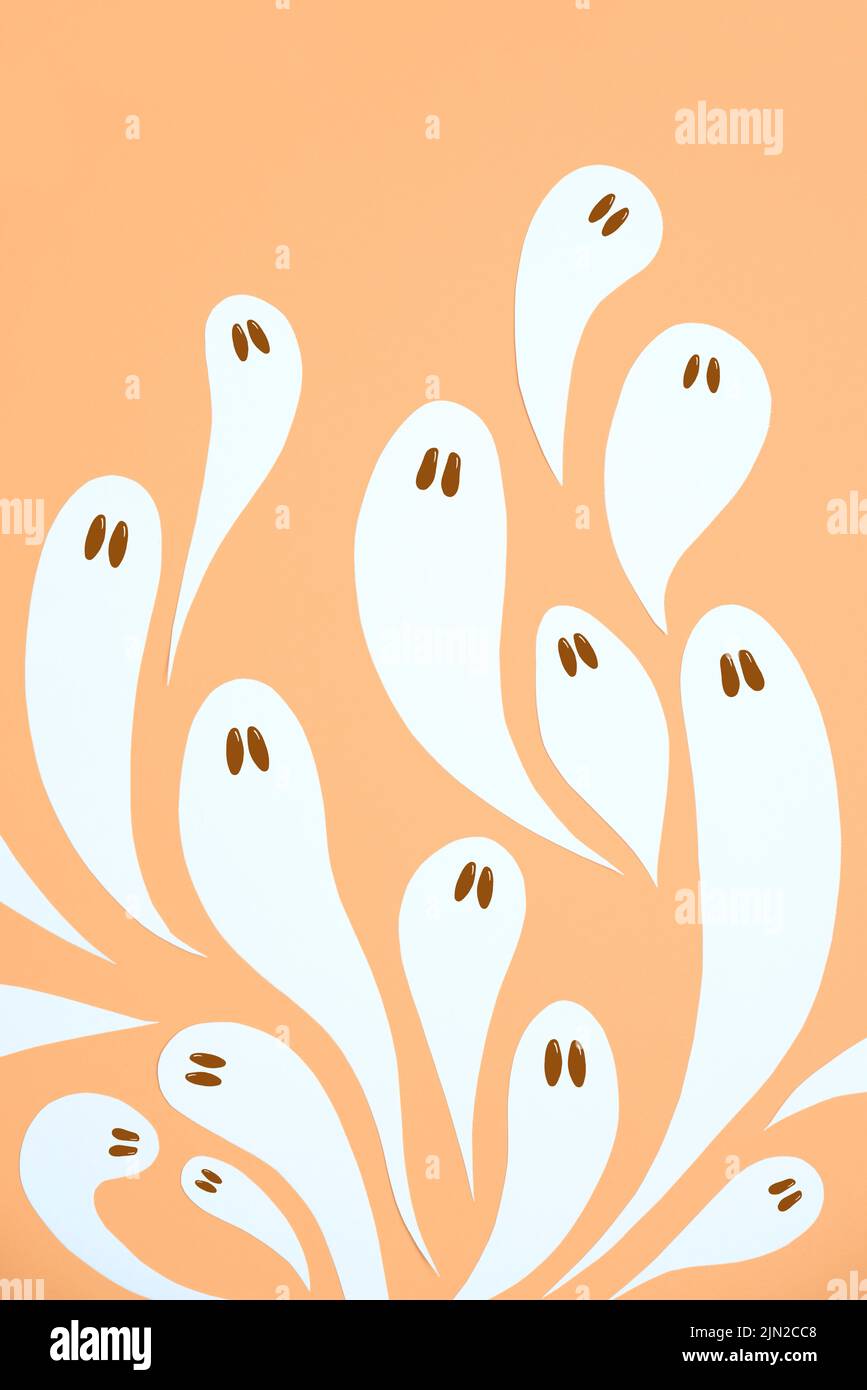Halloween design alla moda, gruppo di simpatici fantasmi bianchi che volano su sfondo color arancio pastello. Foto Stock