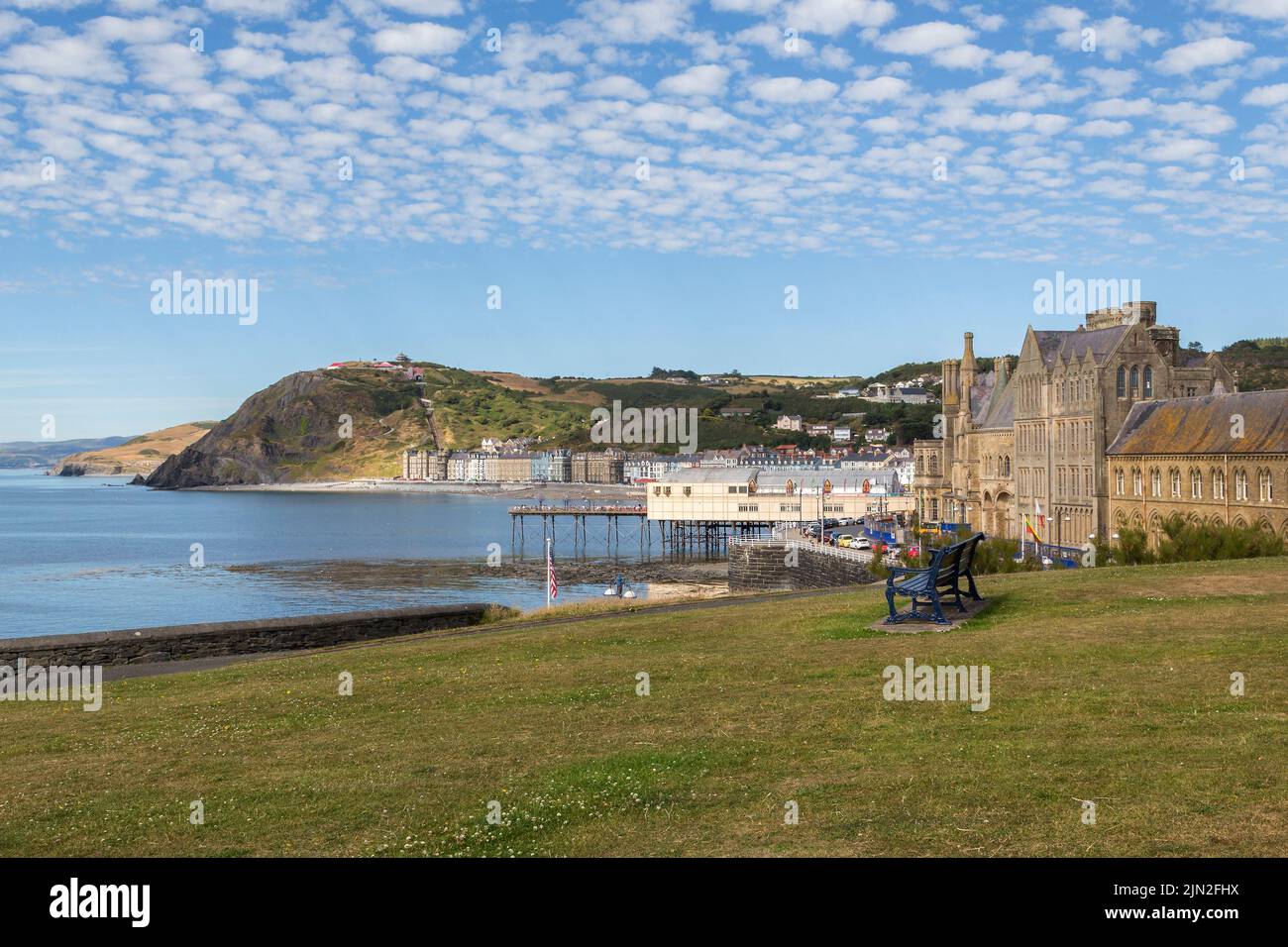 Una vista di Aberystwyth, l'Old College, il molo, il lungomare e la funicolare sulla Constitution Hill possono essere visti sotto un bel cielo di sgombri. Foto Stock