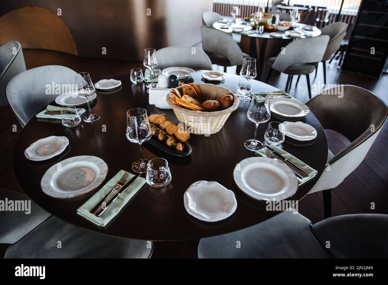 Evento splendidamente organizzato - tavolo rotondo servito banchetto pronto per gli ospiti, tavolo rotondo decorato con piatto vuoto, bicchieri, forchette, tovagliolo. Elegante tavolo da pranzo Foto Stock