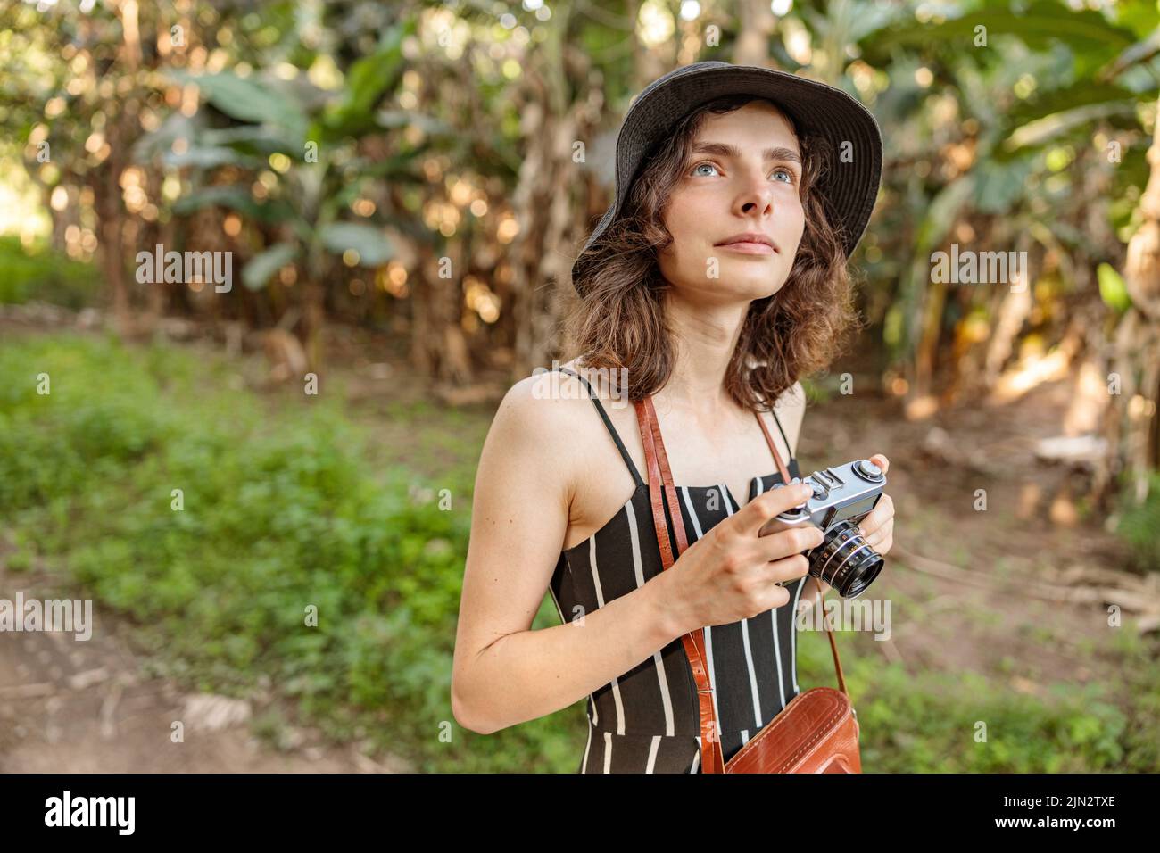 Giovane viaggiatore femminile in cappello nero con macchina fotografica nel parco nazionale africano Foto Stock