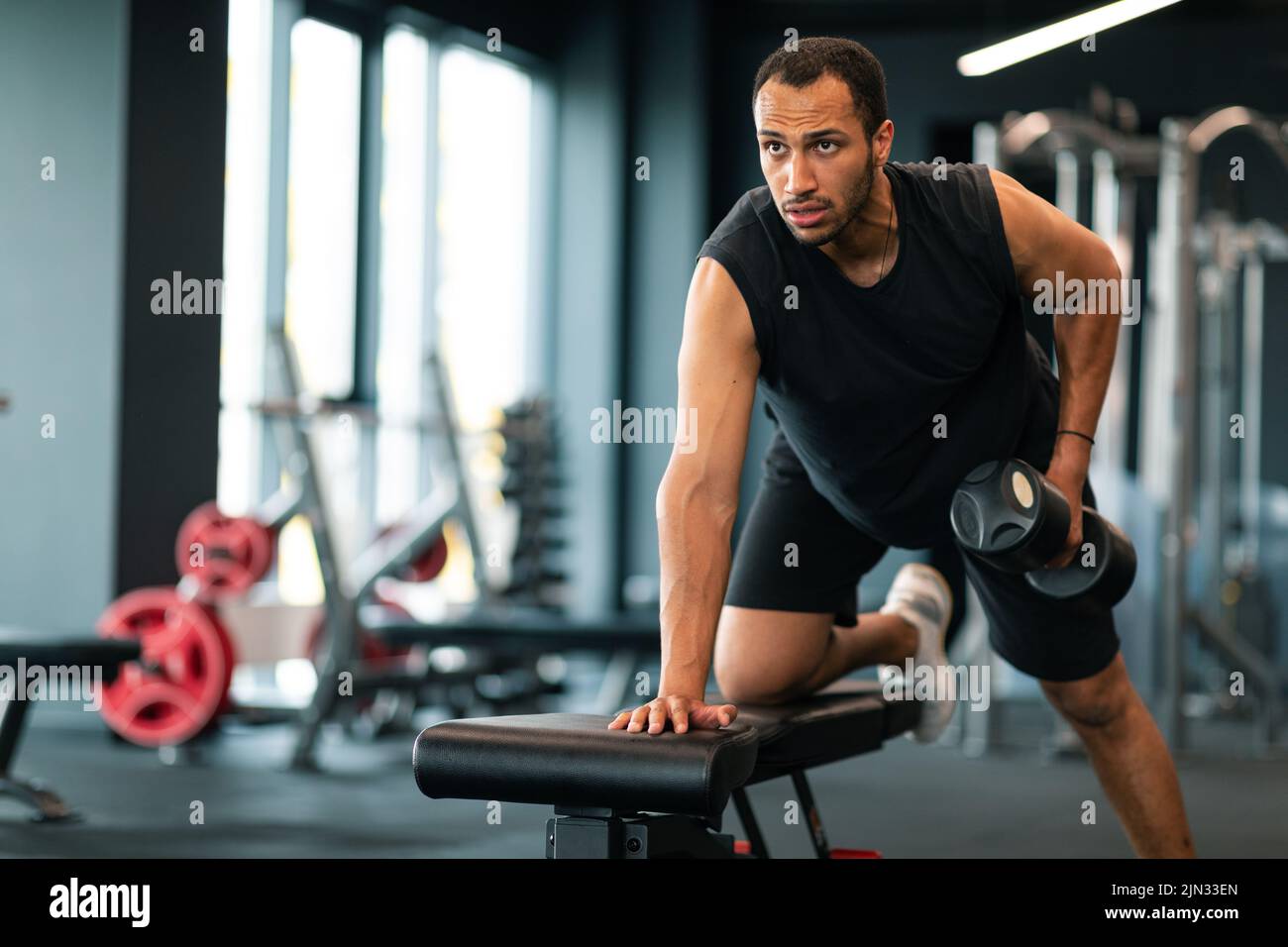 Ritratto di motivata Black Sportsman che si esercita con Dumbbell in palestra Foto Stock