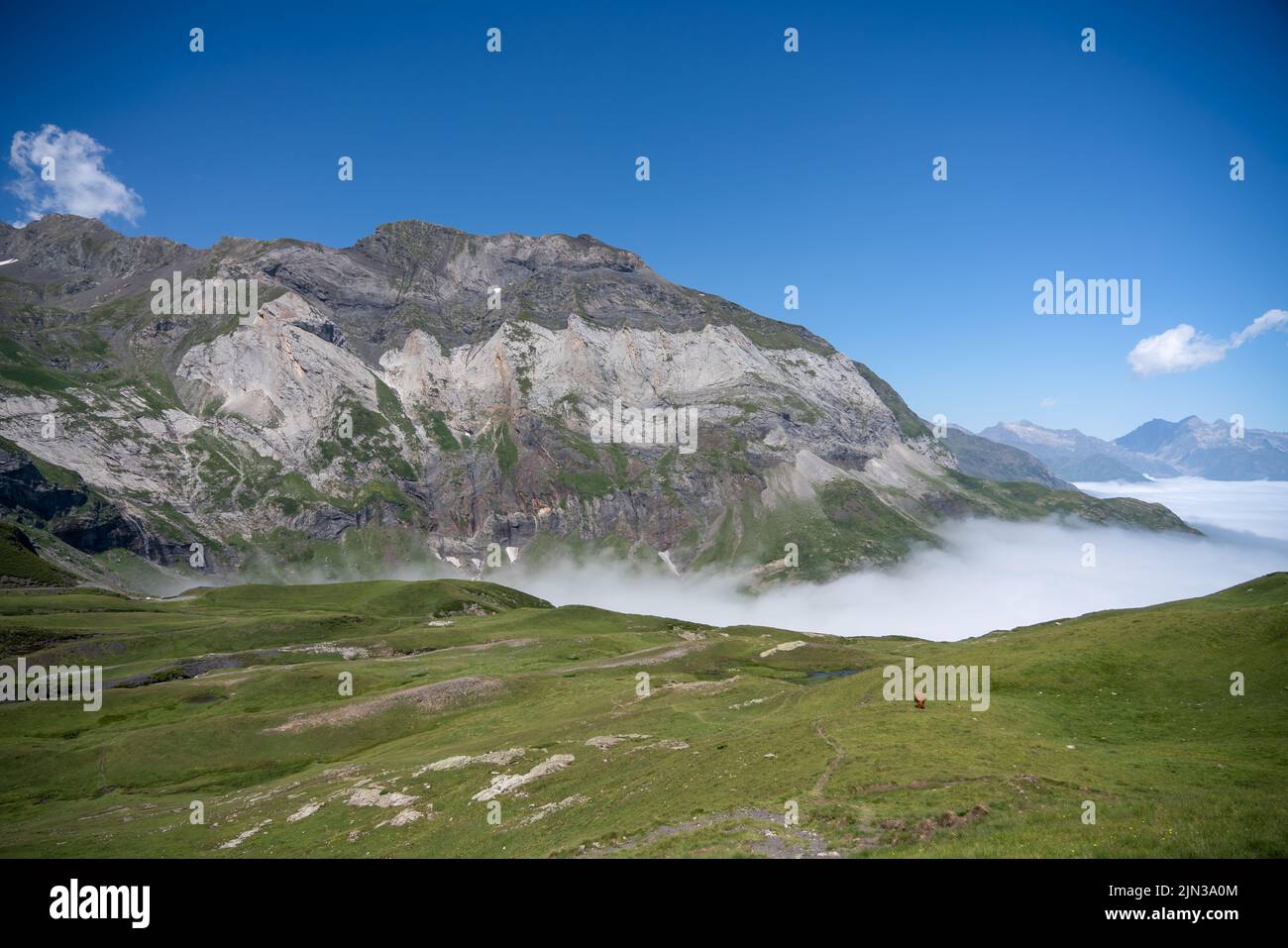 Enourmous valle circolare circondata da alte montagne, il Cirque de Troumouse (Pirenei), nube che riempie la valle sottostante e cielo azzurro chiaro estate Foto Stock