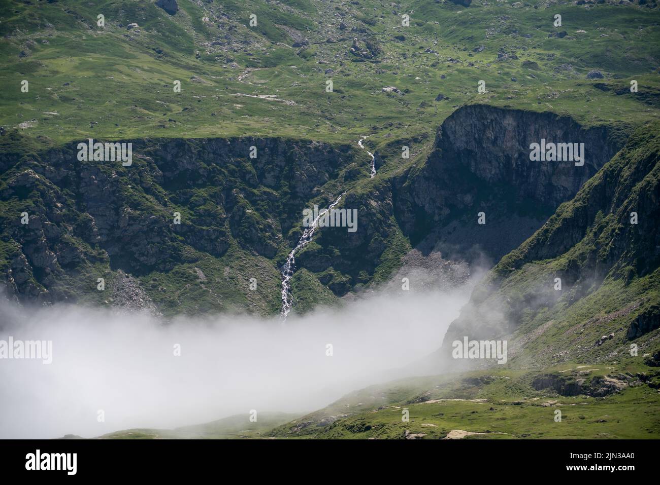 Enourmous valle circolare circondata da alte montagne, il Cirque de Troumouse (Pirenei), nube che riempie la valle sottostante e cielo azzurro chiaro estate Foto Stock