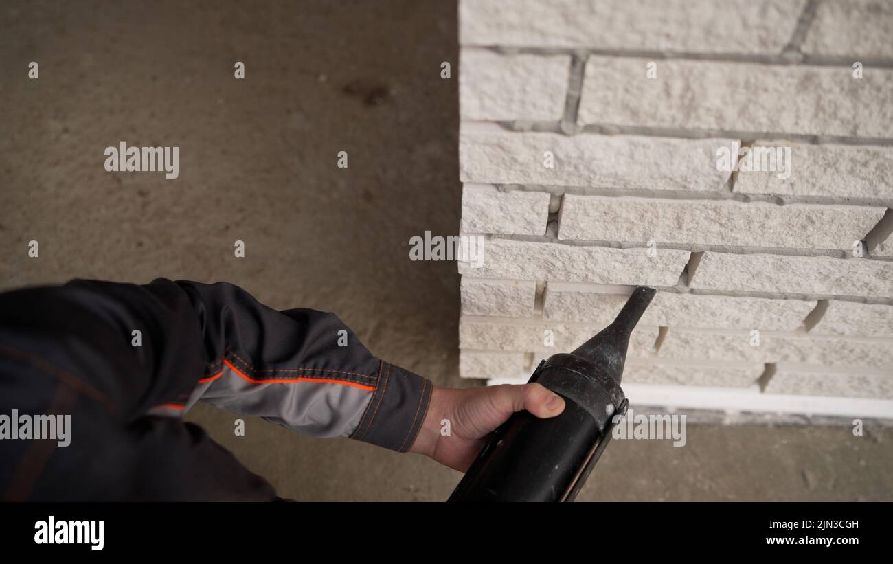 Il processo di applicazione di un primer su una parete mediante un rullo. Applicazione di colla con rullo sulla parete sotto il soffitto. Riempimento dei giunti in brickwor Foto Stock