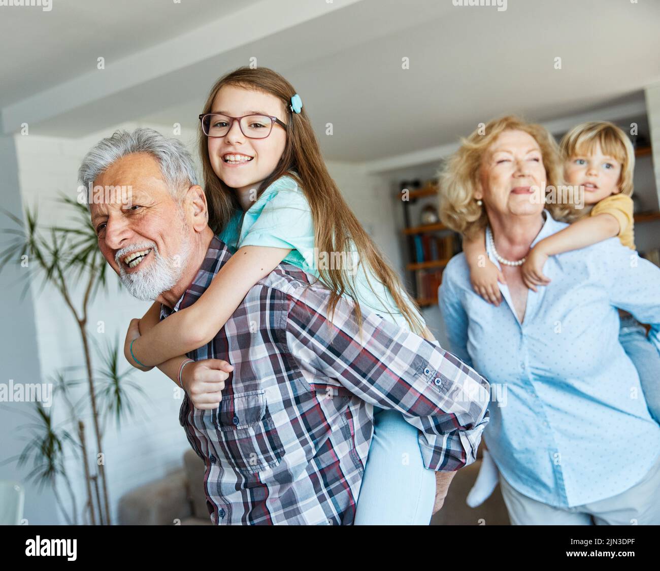 nipote famiglia figlio nonno uomo donna nonno felice insieme nonna ragazza anziano ragazzo sorridente nonna piggyback Foto Stock