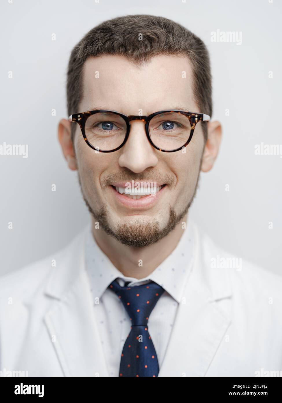 Ritratto di giovane felice barbuto medico maschile sorridente con occhiali isolati su sfondo bianco Foto Stock