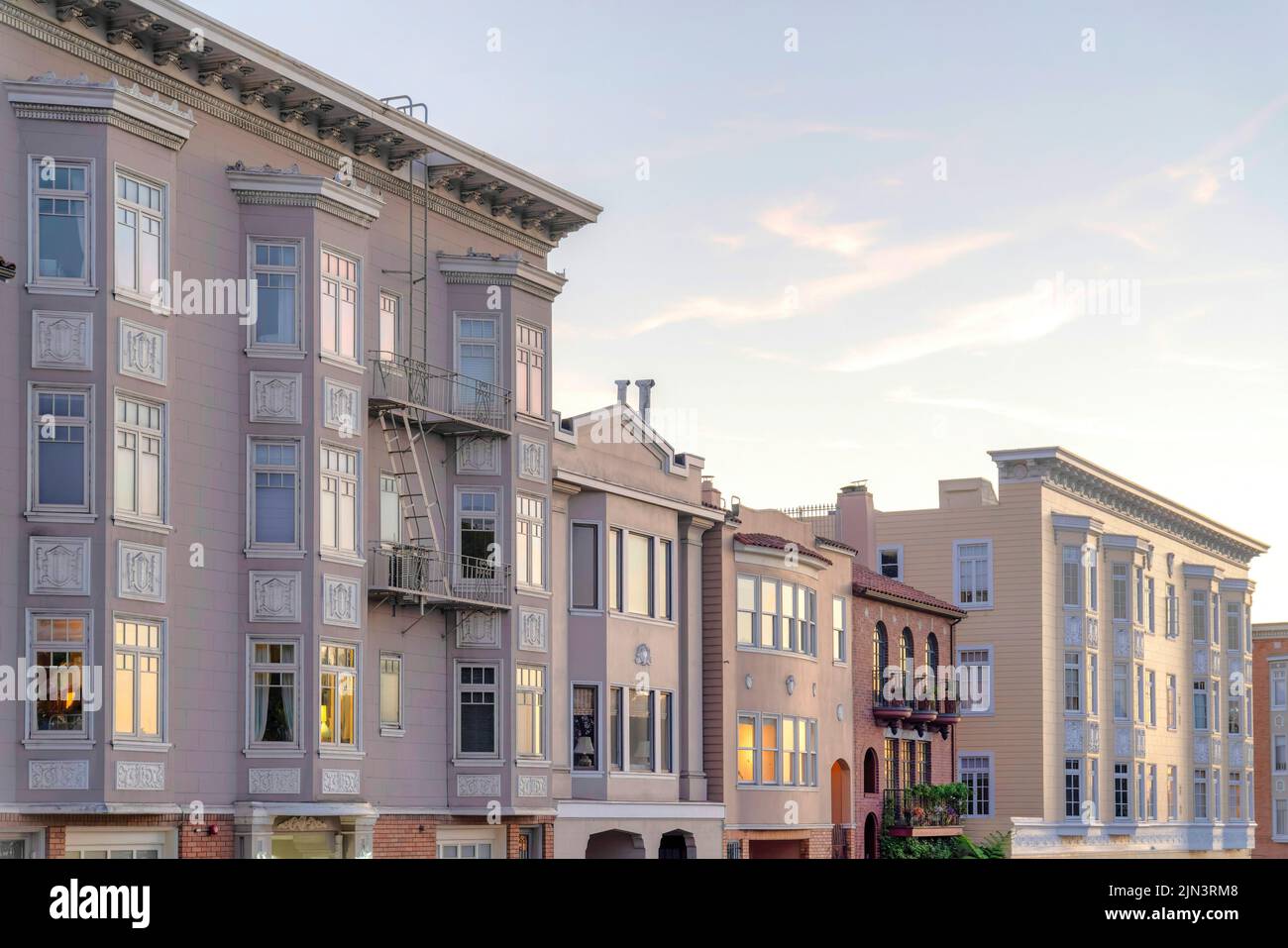 Appartamenti vittoriani e case cittadine con riflesso del tramonto sulle sue finestre a San Francisco, CA. Ci sono case cittadine nel mezzo di due appartamenti Foto Stock