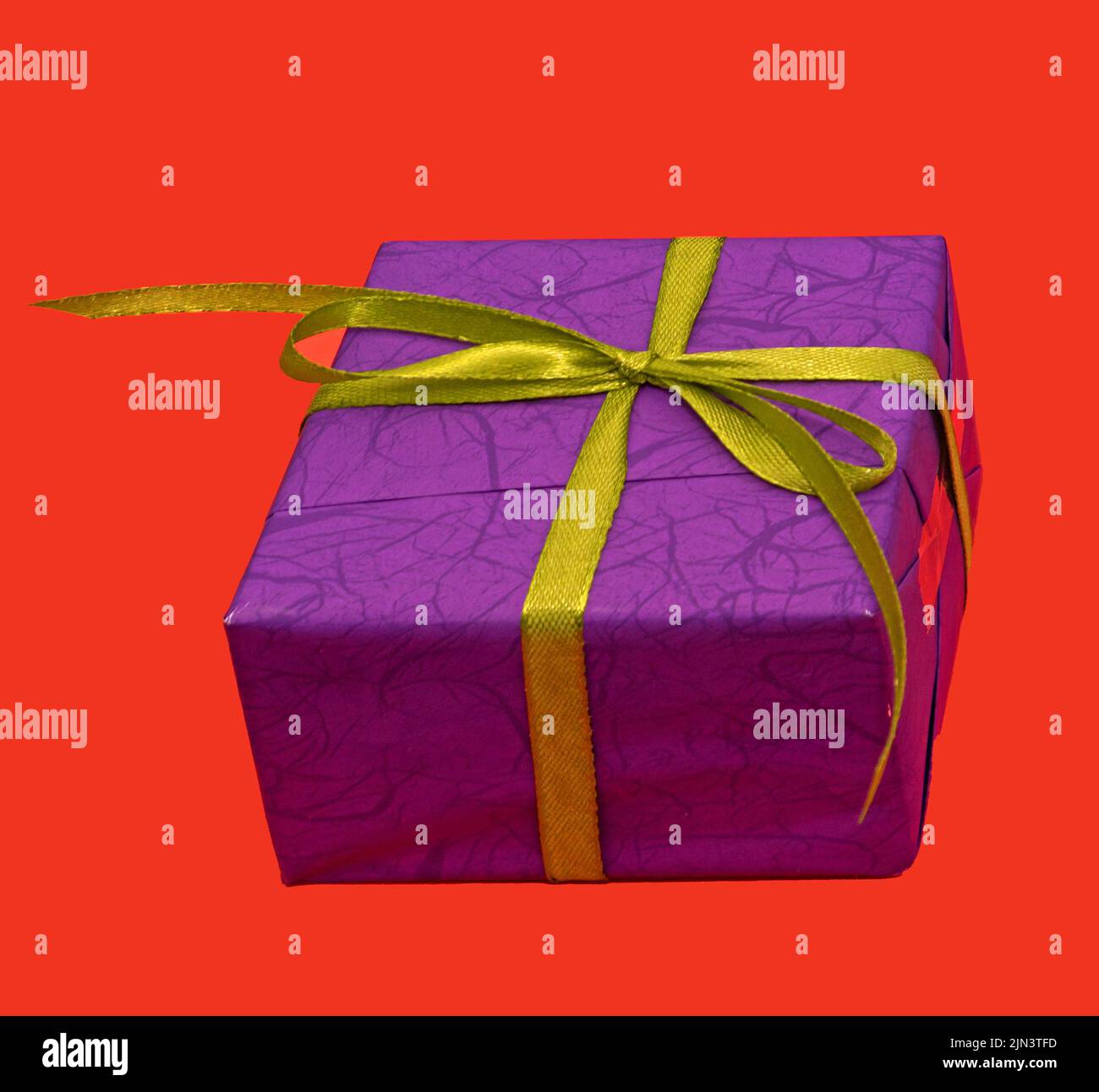 Confezione regalo viola con nastro verde isolato su sfondo rosso Foto Stock