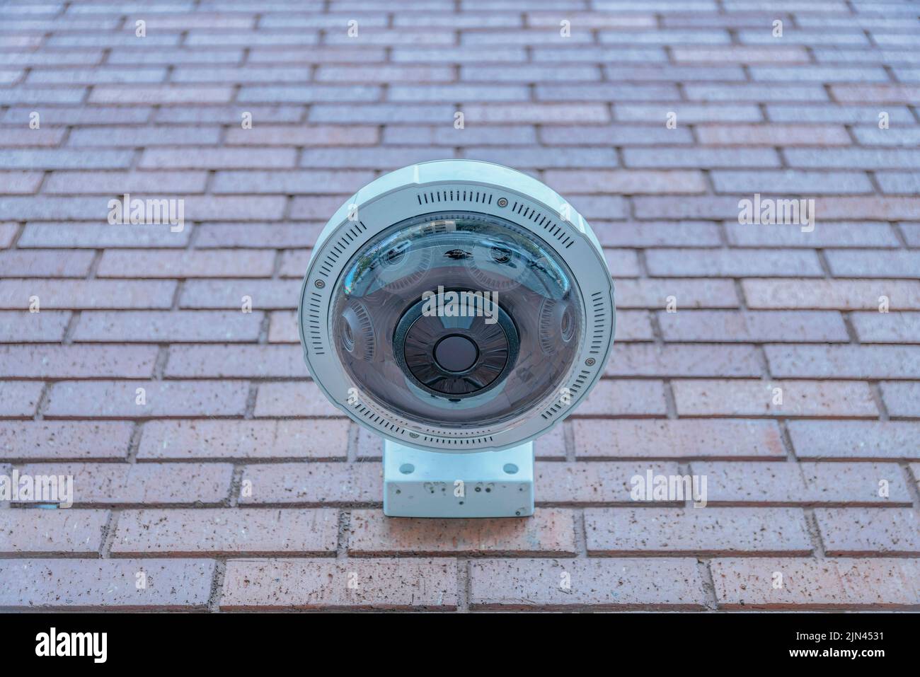 Vista della telecamera cctv panoramica montata a parete dal basso a San Francisco, California. Primo piano dell'obiettivo della telecamera di sicurezza contro la parete di mattoni rossi con Foto Stock
