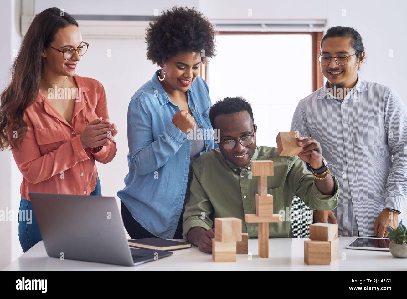 Fare ondate nel settore con un nuovo modello di business. Un gruppo di giovani uomini d'affari che hanno un incontro con i blocchi di costruzione in un ufficio moderno. Foto Stock