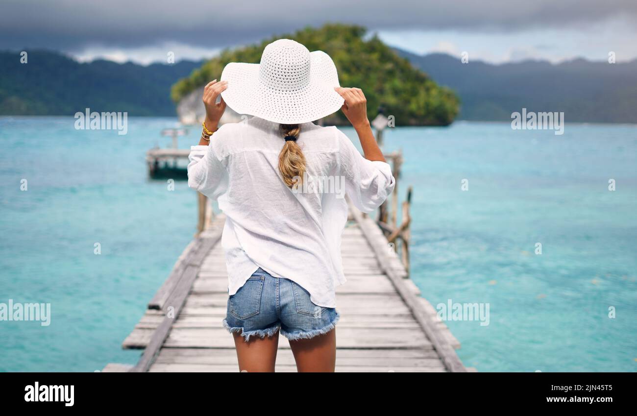 Infine, un po' di riposo necessario. Dietro l'inquadratura di una donna irriconoscibile in piedi su una passerella che si affaccia sull'oceano durante la vacanza. Foto Stock