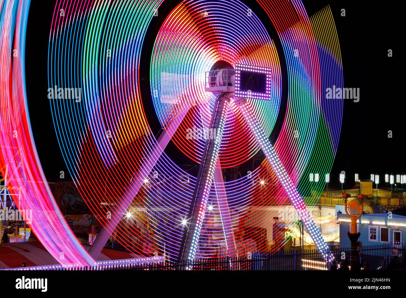 Asse pendolo oscillazione giro in movimento di notte con coloratissimi percorsi di luce Foto Stock