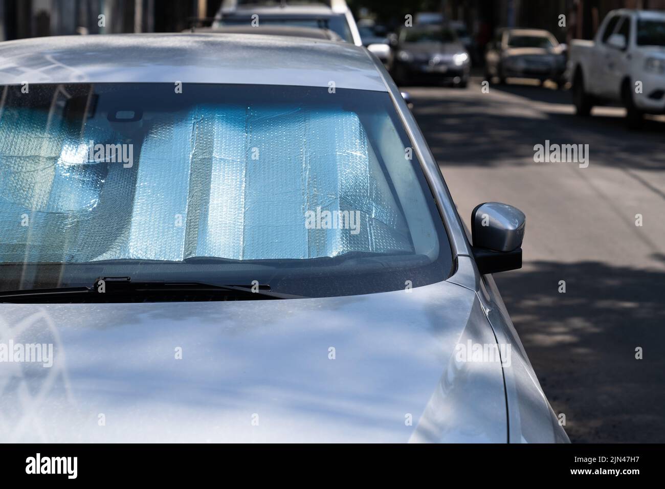 Superficie riflettente protettiva sotto il parabrezza dell'auto nelle giornate calde, riscaldata dai raggi del sole all'interno dell'auto Foto Stock