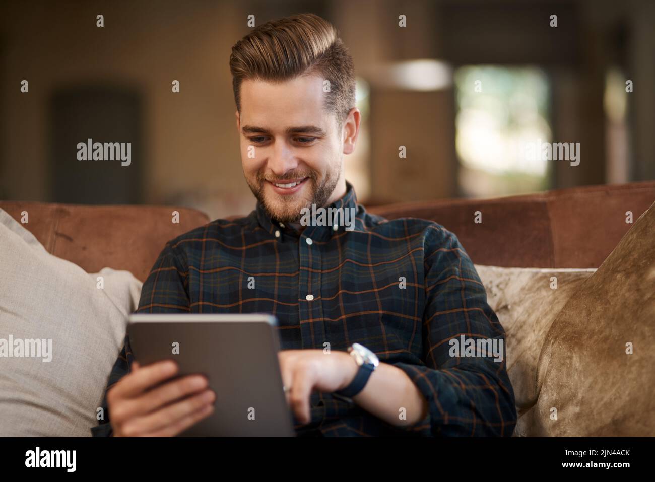 Ho tutto l'intrattenimento di cui ho bisogno proprio qui: Un giovane che si rilassa sul divano di casa. Foto Stock