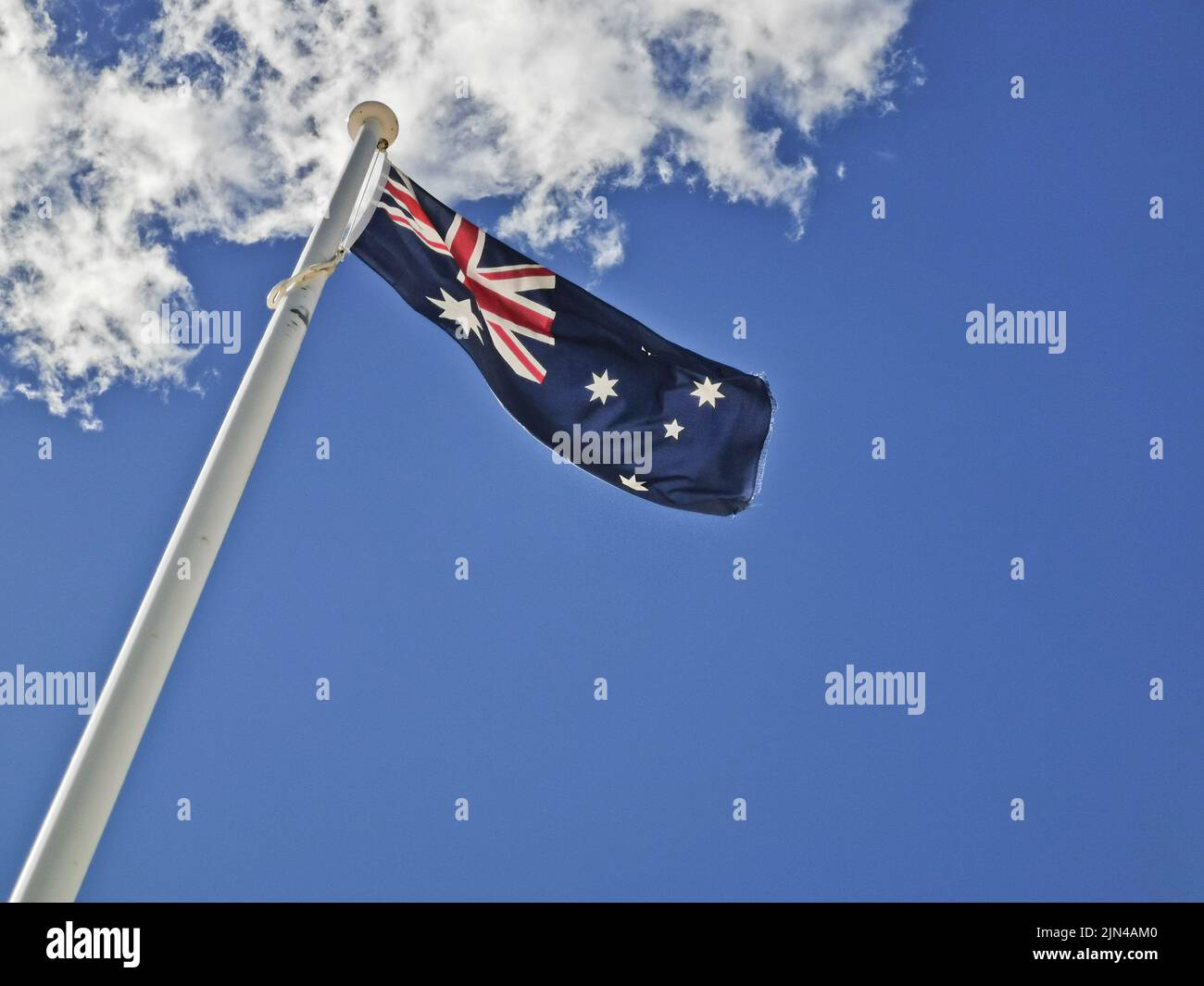La bandiera nazionale dell'Australia consiste nella costellazione delle stelle Union Jack e Southern Cross in cielo blu giorno soleggiato con nuvola bianca Foto Stock