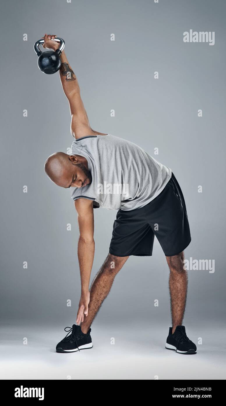 Lavorate su di voi stessi. Un giovane sportivo che si allena con pesi su sfondo grigio. Foto Stock