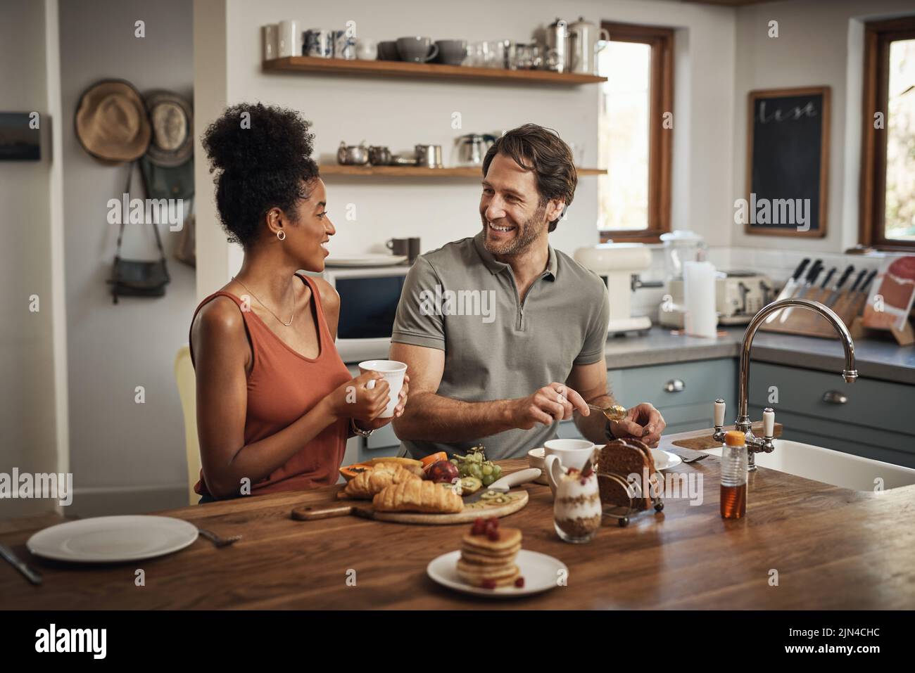 Sembra una bella giornata, una giovane coppia affettuosa che fa colazione in cucina a casa. Foto Stock