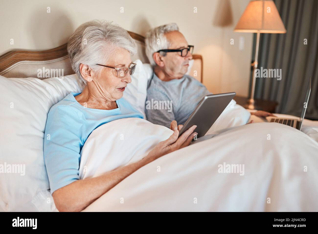 Avete visto le notizie stamattina. Una coppia anziana seduta a letto insieme e utilizzando la tecnologia in una casa di cura. Foto Stock