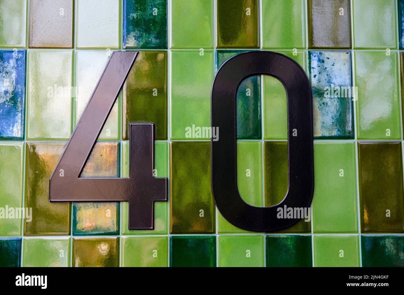La cifra 40 fuori da un blocco di uffici nel centro di Londra. Numeri di bronzo posti su piastrelle di ceramica verde. Foto Stock