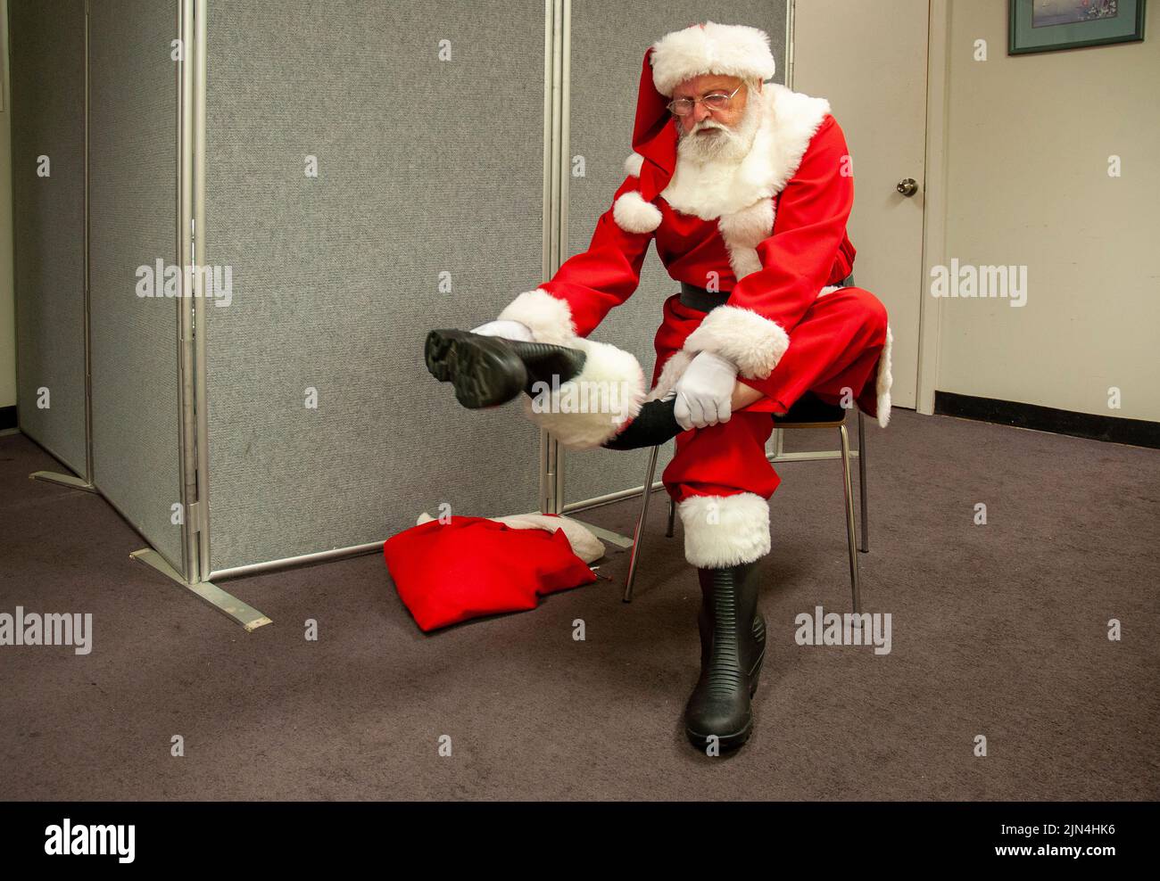 Un grande magazzino Babbo Natale che porta via i suoi stivali, dietro le quinte in un centro commerciale a Hobart, Tasmania, Australia durante il periodo di shopping pre-Natale Foto Stock