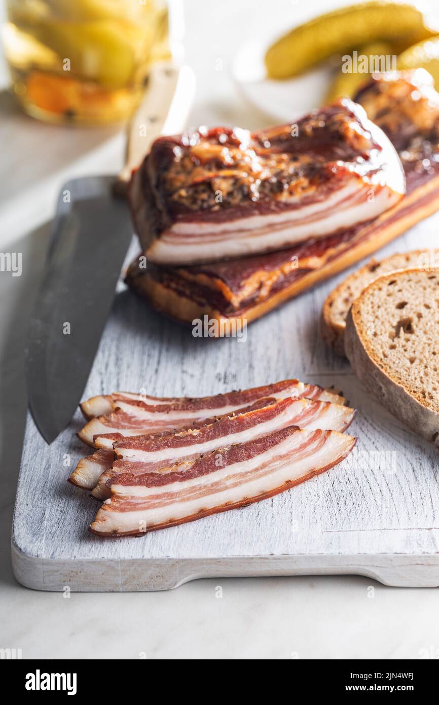 Pancetta affumicata a fette su un tagliere. Foto Stock