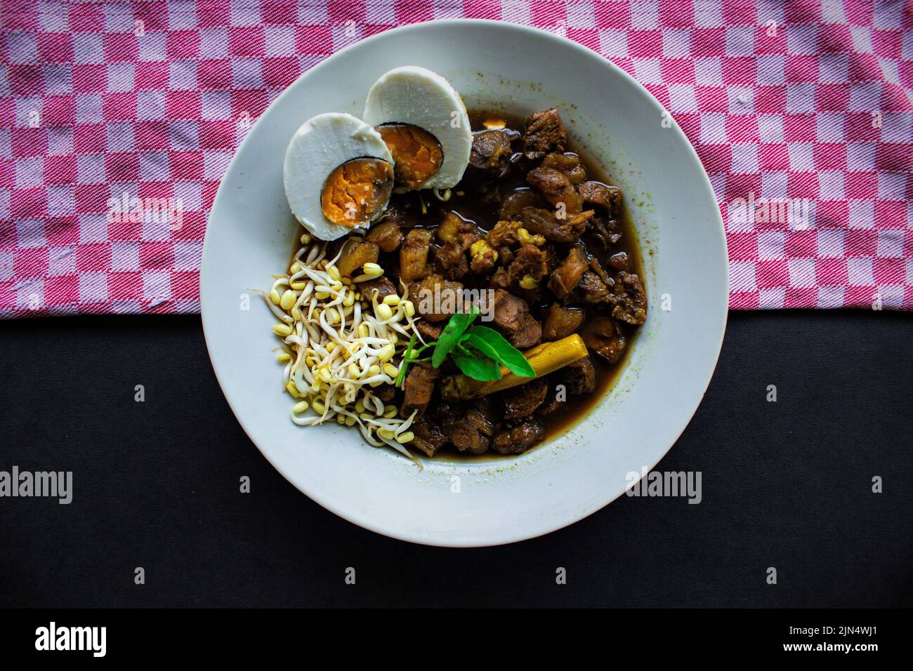 Il riso Rawon o Nasi Rawon/Rawon è una tradizionale zuppa di manzo indonesiana, servita con germogli, uova salate, condimento kluwek. Da Java est. Isolato Foto Stock