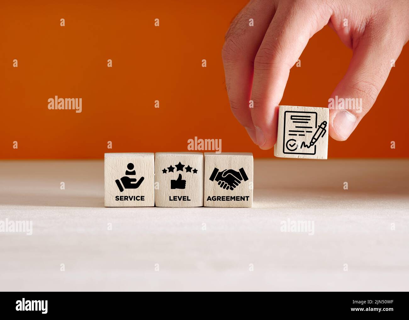 Concetto aziendale SLA del contratto del livello di servizio. Mano mette i cubetti di legno con i simboli del contratto del livello di servizio. Foto Stock