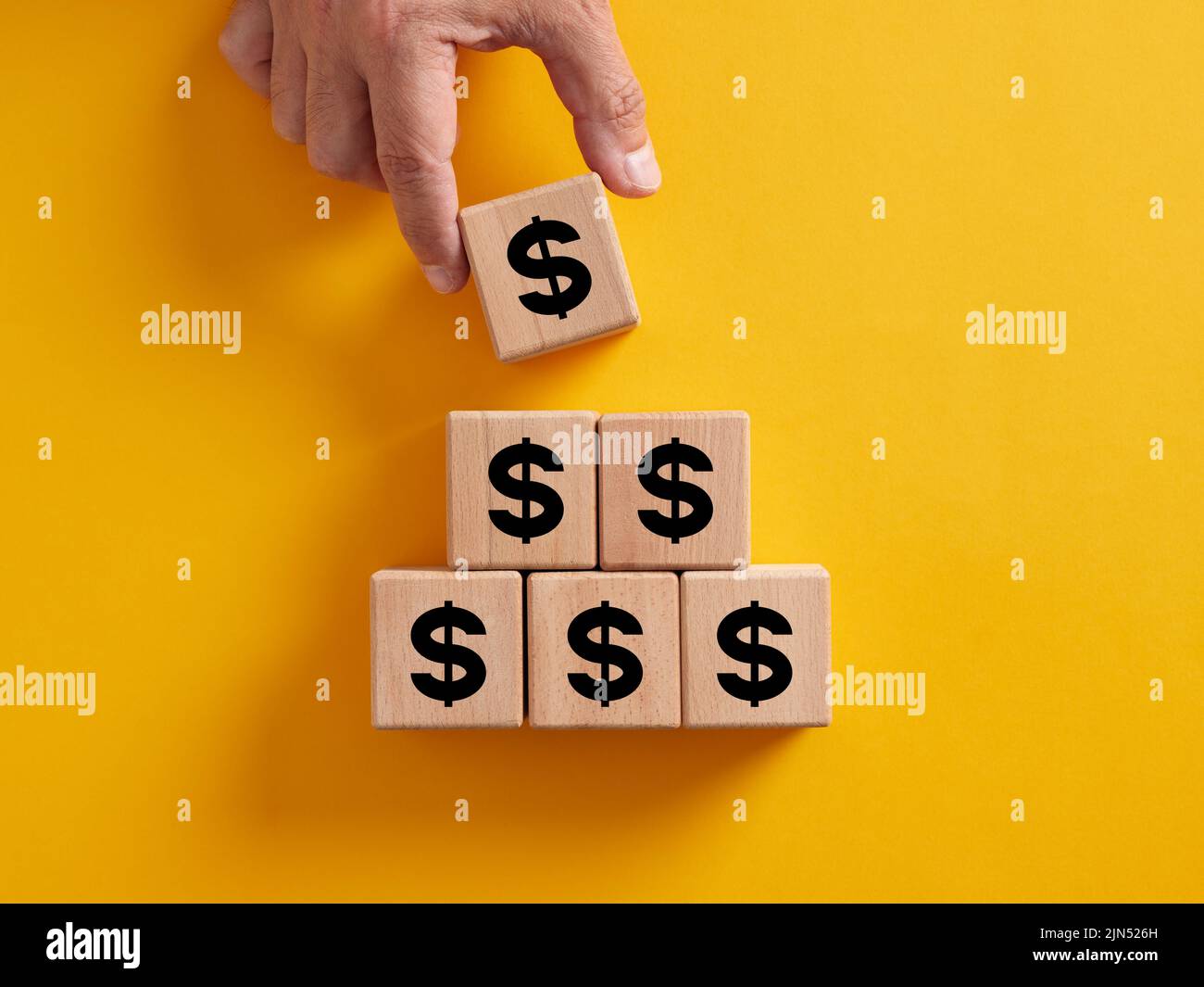 Mettere a mano cubi di legno con segno US dollari disposti in scala piramidale. Aumentare il profitto aziendale, la ricchezza e i concetti di risparmio di denaro. Foto Stock