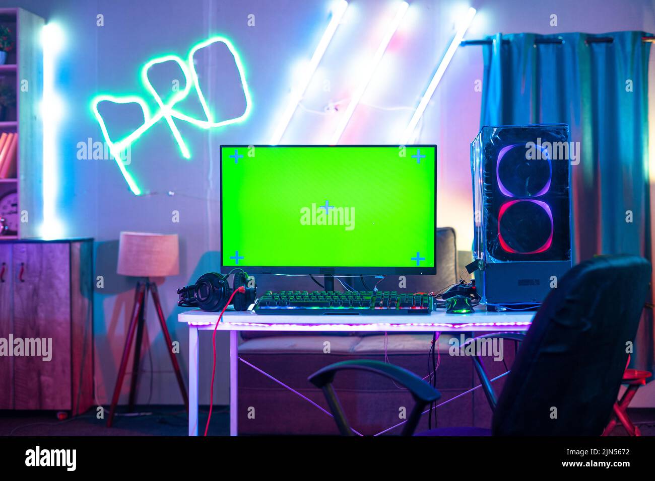 Monitor con schermo verde e CPU in esecuzione nella sala dei giocatori con illuminazione al neon - concetto di hobbista, live streaming e intrattenimento. Foto Stock