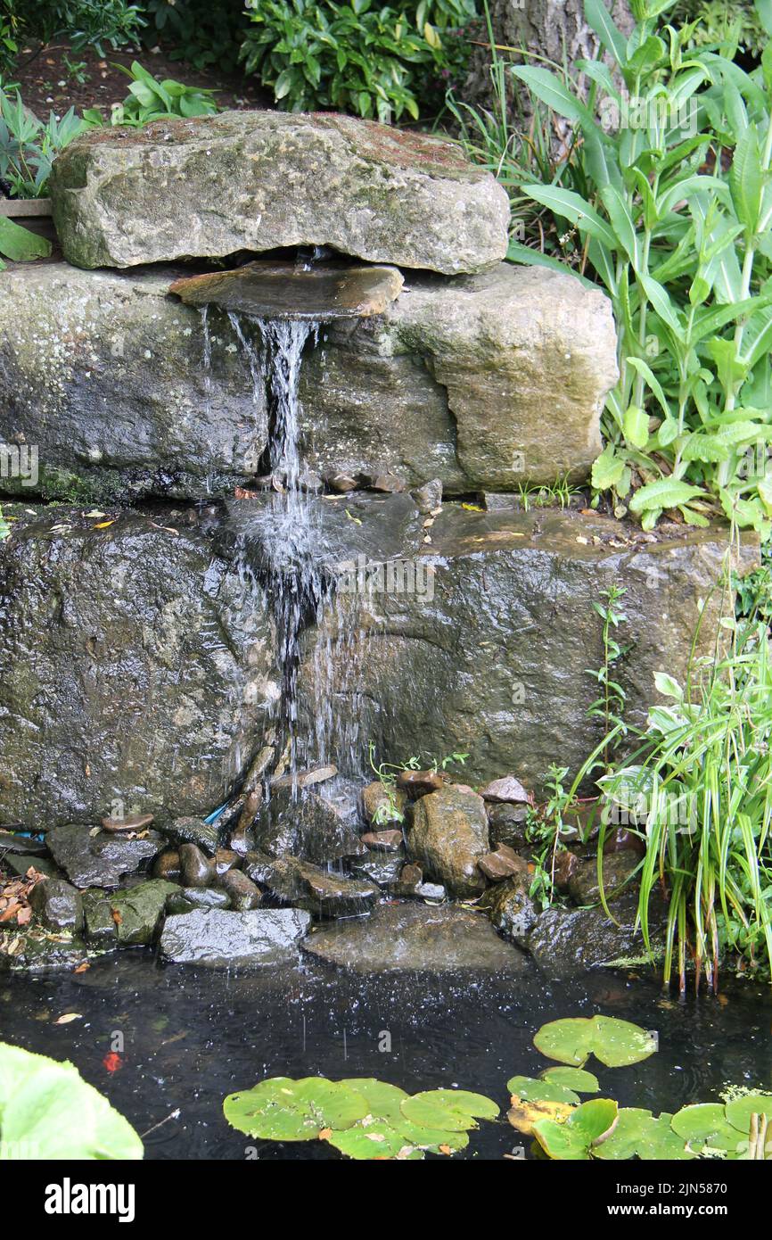 Una pretty Ornamental Stone e Pebble Garden Waterfall. Foto Stock