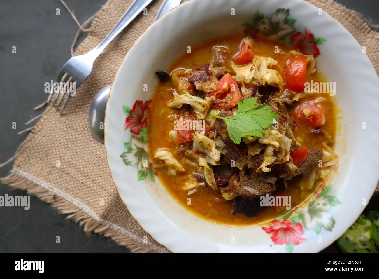 'Capra Curry o gulai kambing, cibo da asia. Delizioso curry di carne di capra servito in un bowl.served con pomodoro, condimento, sedano e cavolo' Foto Stock