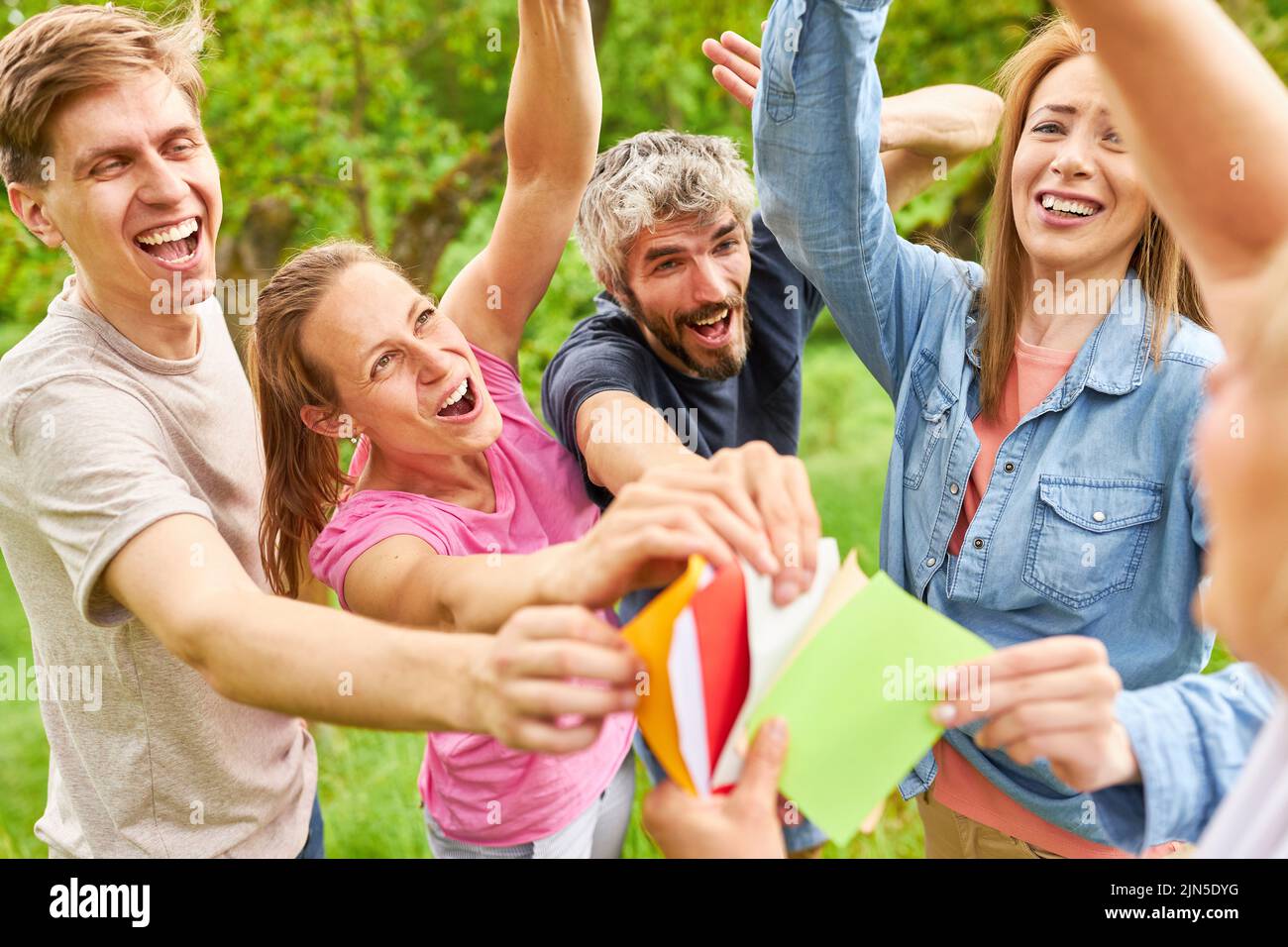 Giovani pieni di entusiasmo nel gioco di team building scegliendo le carte colorate Foto Stock