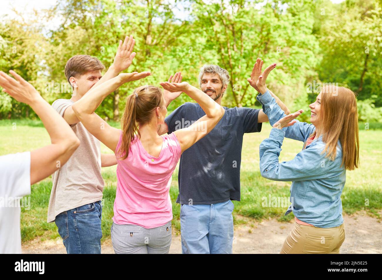 I giovani all'evento di team building fanno cinque per motivare o celebrare il successo Foto Stock