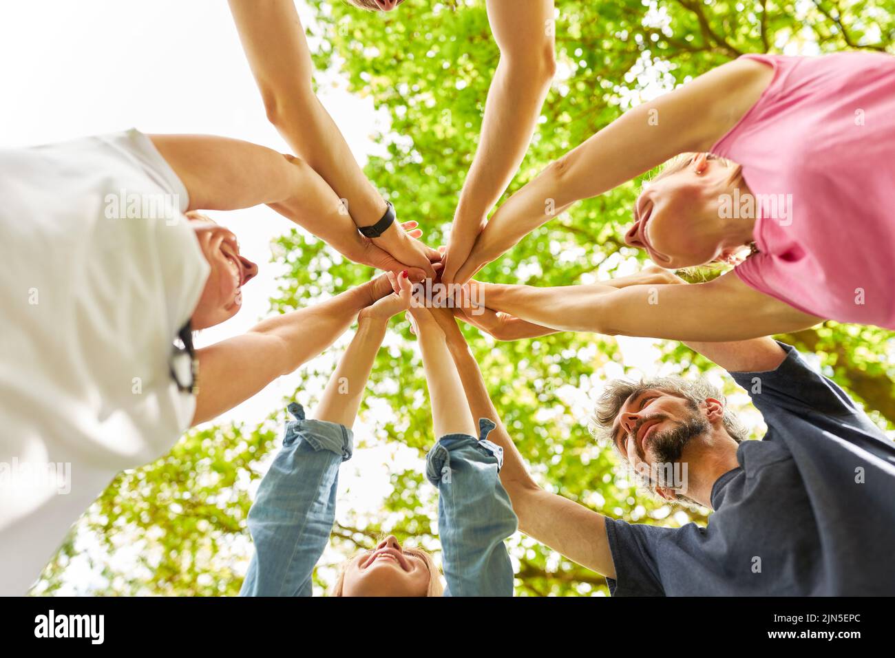 Gli amici si alzano in cerchio e si stringono le mani per creare un team building e una sinergia Foto Stock
