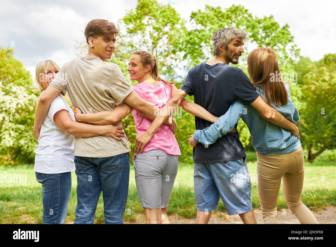 Cinque amici si affiancano in un abbraccio su una passeggiata nella natura Foto Stock
