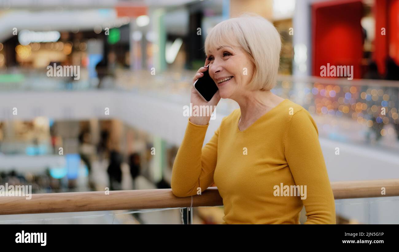 Matura donna felice parla amichevole al telefono risponde chiamata comunica con la famiglia utilizzando smartphone gioiosa di mezza età colloqui a distanza gossiping su Foto Stock