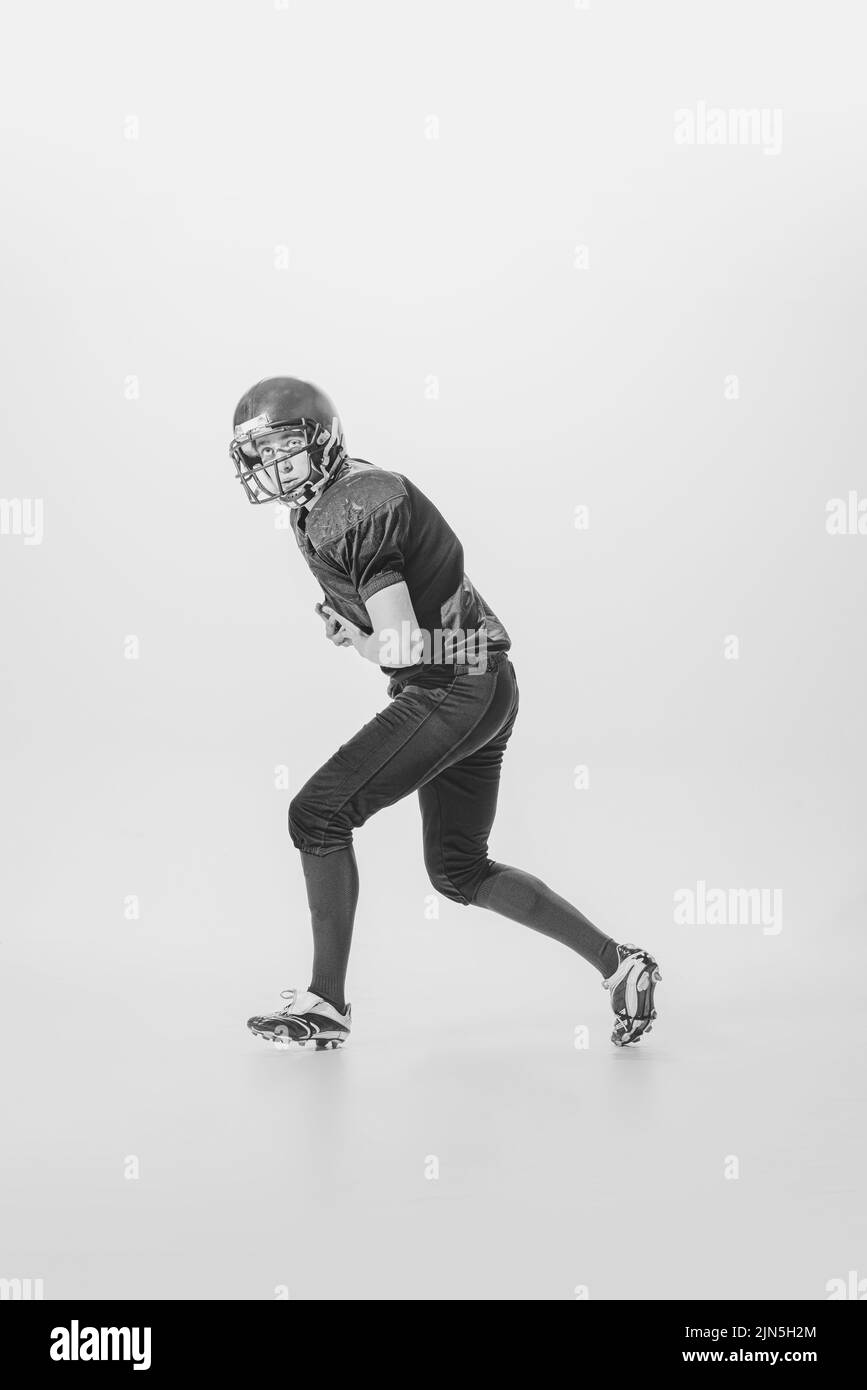 Ritratto di giovane concentrato, giocatore di calcio americano in movimento, azione. Fotografia in bianco e nero. Centrale-posteriore Foto Stock