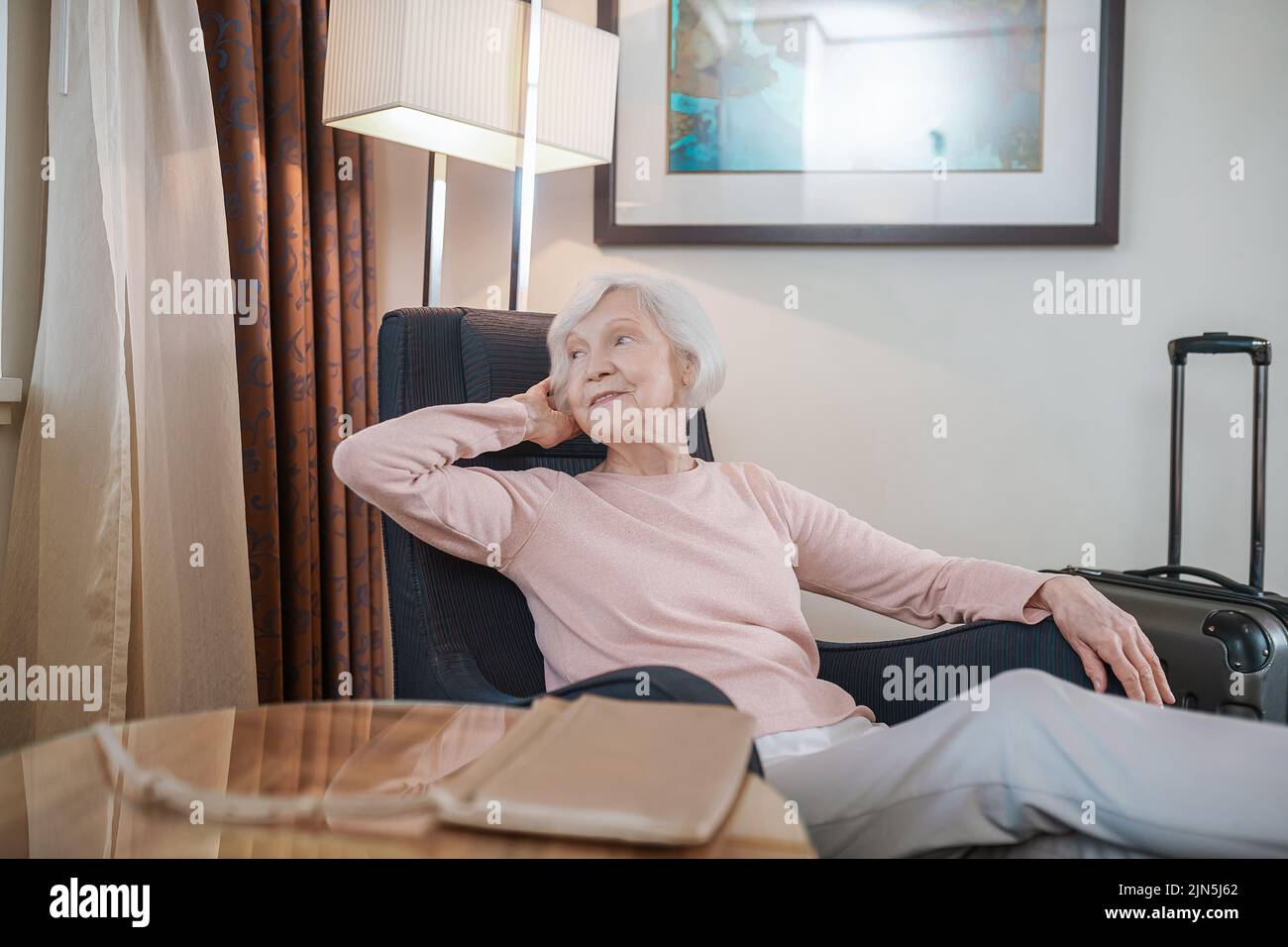 Donna anziana con capelli corti in una camera d'albergo Foto Stock