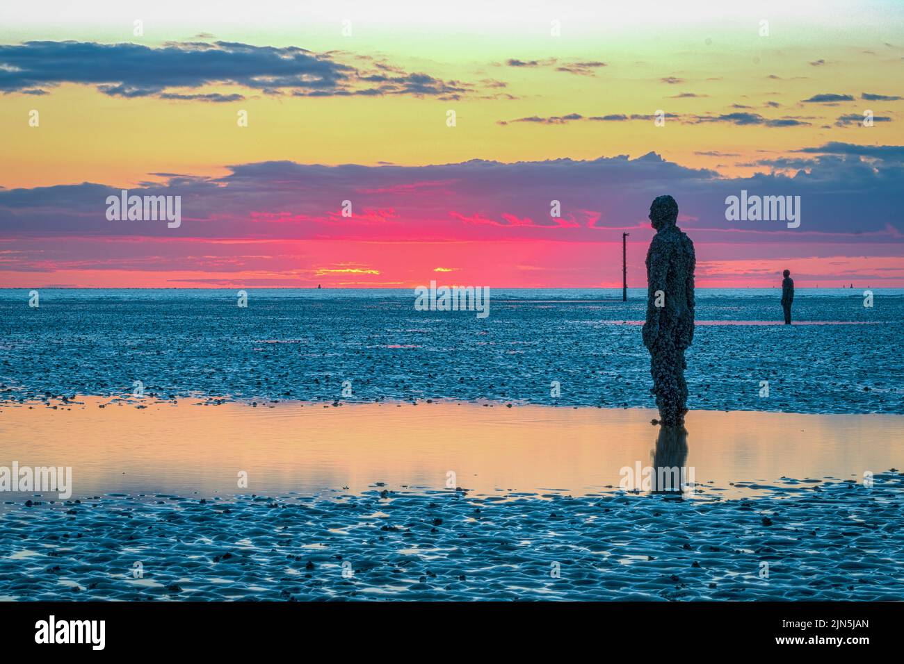 Un uomo di ferro in un altro posto di Anthony Gormley a Crosby, Inghilterra al tramonto Foto Stock