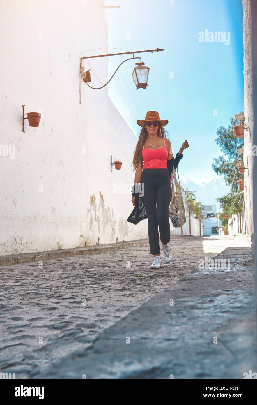 Bella bruna giovane indossando un cappello e camminando attraverso la vecchia strada di Arequipa, Perù. Concetto di viaggio Foto Stock