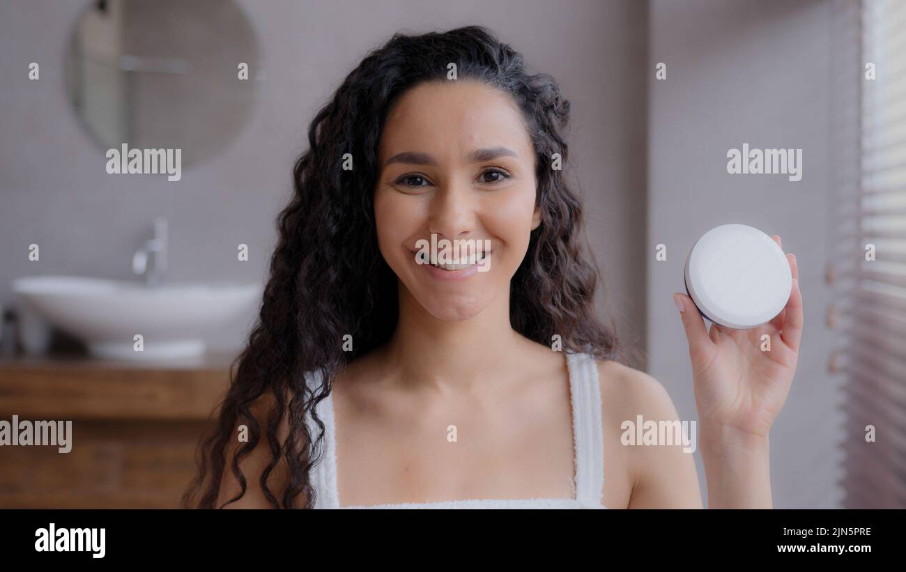 Primo piano giovane attraente Happy hispanic donna in piedi in bagno guardando la macchina fotografica sorridente pubblicità prodotti per la cura della pelle puntando al vaso Foto Stock