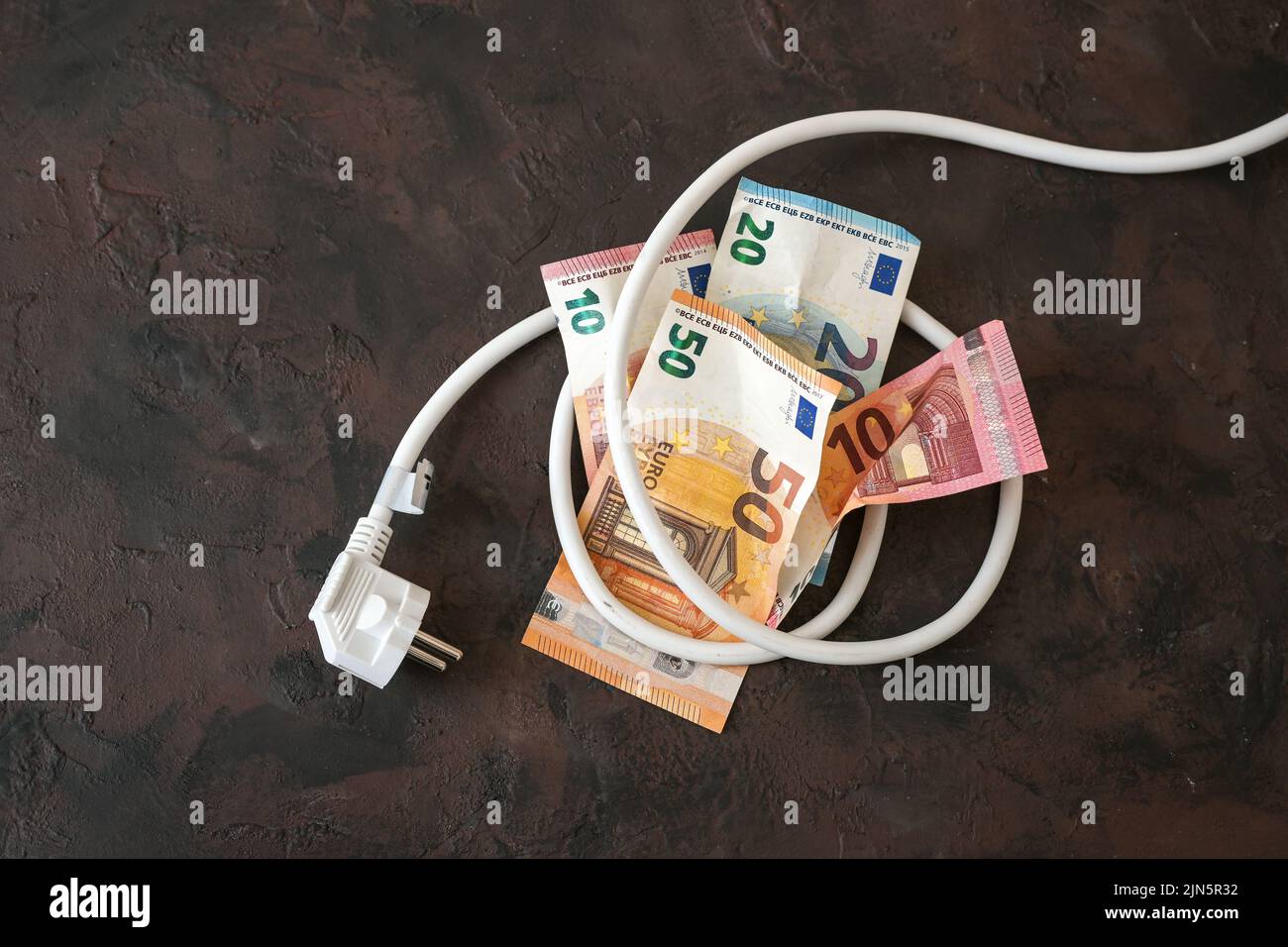 Pacchetto di banconote in euro legate a un cavo elettrico con spina, concetto di efficienza energetica, consumo energetico e aumento dei costi dell'elettricità Foto Stock