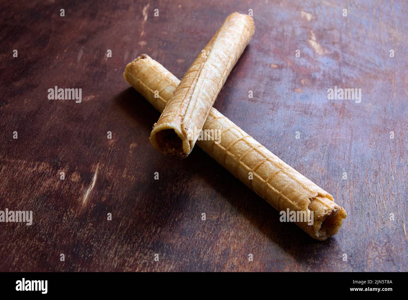 Rotoli di cialda di wafer riempiti con crema si trovano sulla parte superiore del tavolo da cucina in legno. Foto Stock