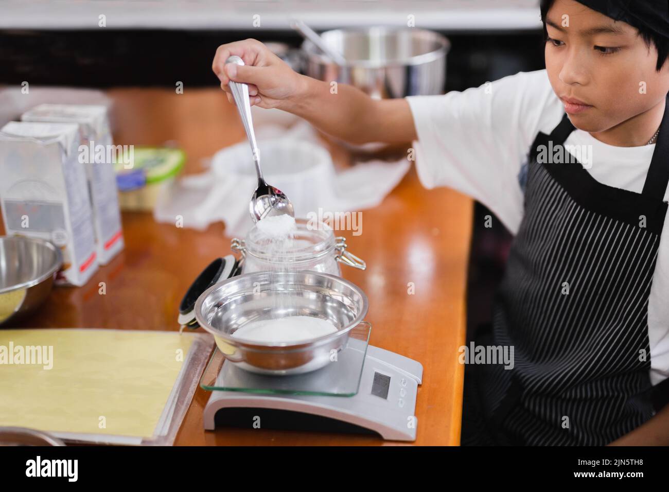 Giovane ragazzo misurare ingrediente per la cottura in cucina. Foto Stock