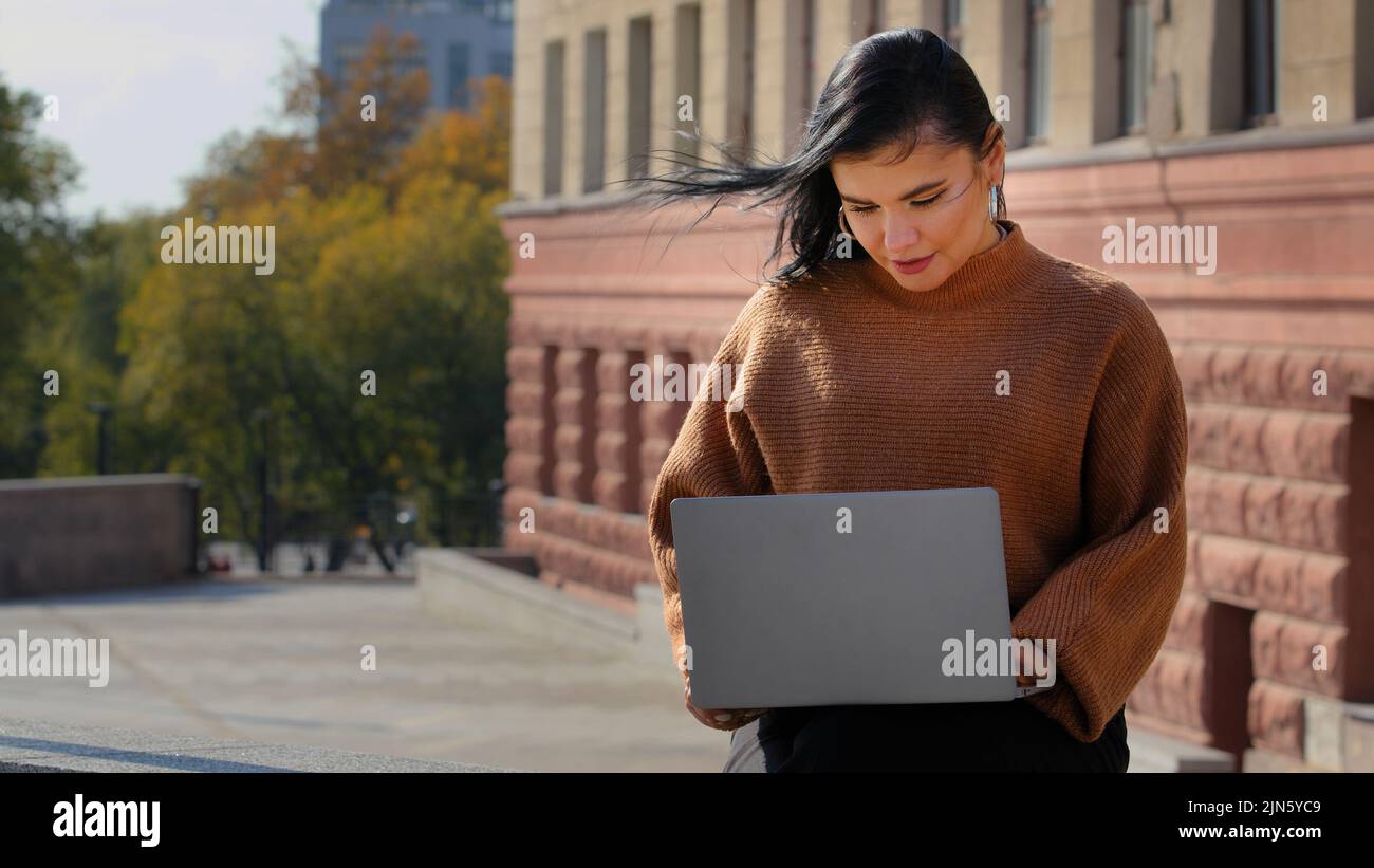 Giovane donna d'affari studente freelance seduto all'aperto leggere e-mail sul portatile sorridendo buone notizie si sente felice gode di processo di navigazione sul web Foto Stock