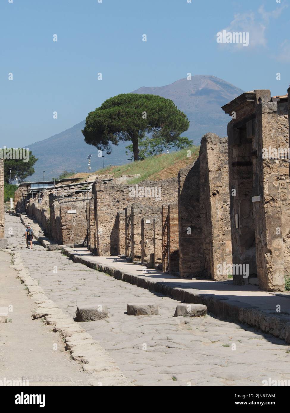 Il turista visita il sito di scavi di Pompei con il vulcano Vesivio sullo sfondo. Pompei, Campania, Italia Foto Stock